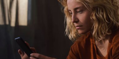 A blond woman looking at her phone, having a sad face as example for signs he doesn't want a relationship with you