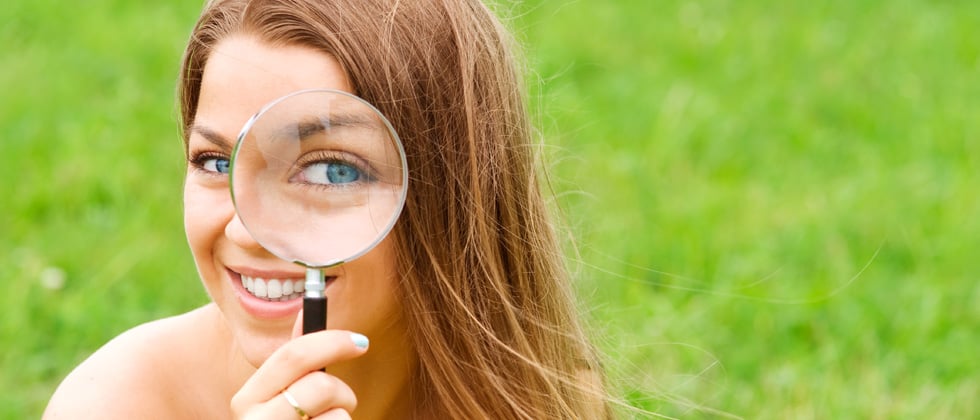 A woman holding a magnifying glass up to one eye
