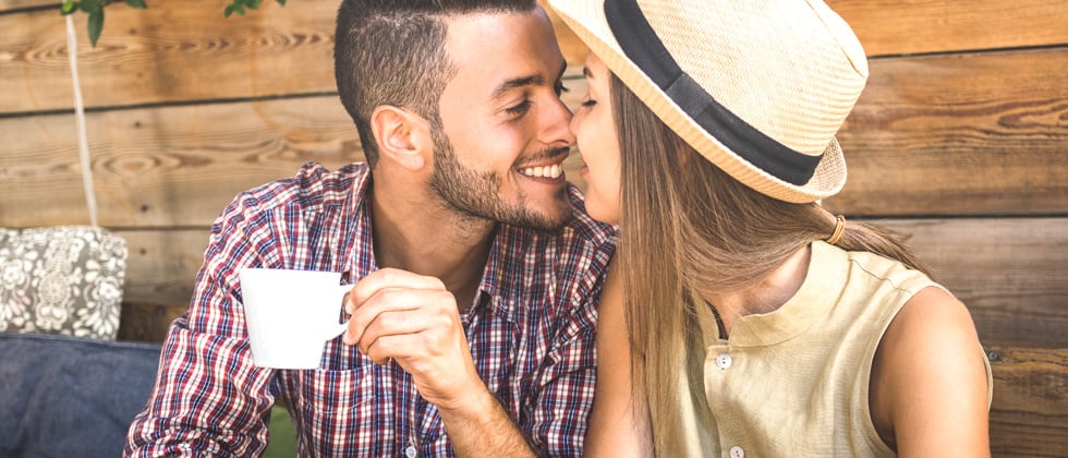 A young couple about to share a kiss while on a coffee date outside