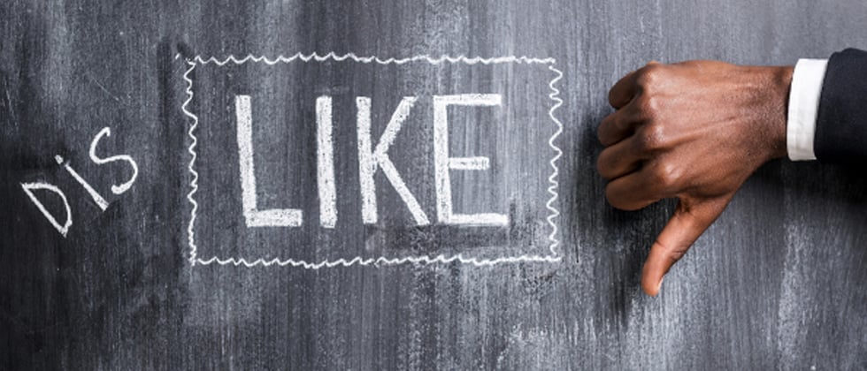 The word DISLIKE written on a chalkboard with a thumbs down sign