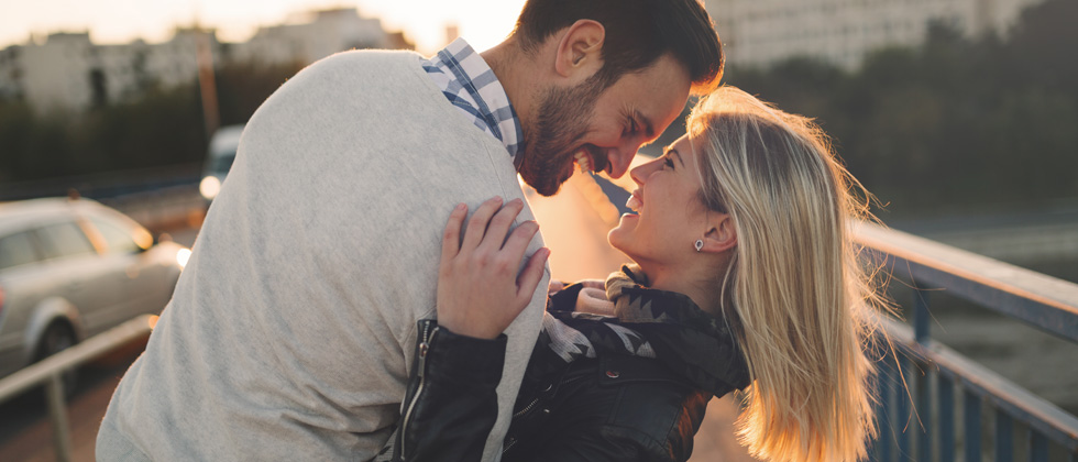 A couple standing on a bridge about to engage in a kiss