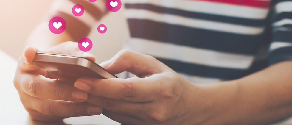 A guy on his phone with heart symbols coming out of it