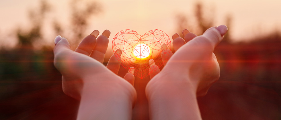 Someone holding up a wireframed heart with the sun in the middle of it