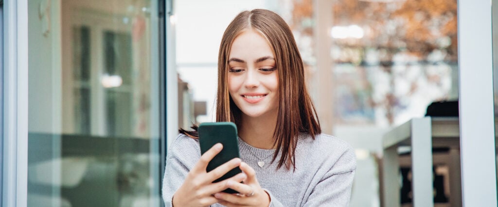 Woman smiling looking at her mobile phone looking for online dating tips for her profile