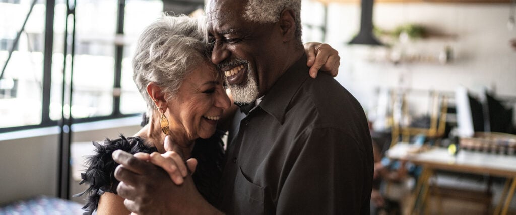 Older couple lie in each other arms and laugh as symbol what is love