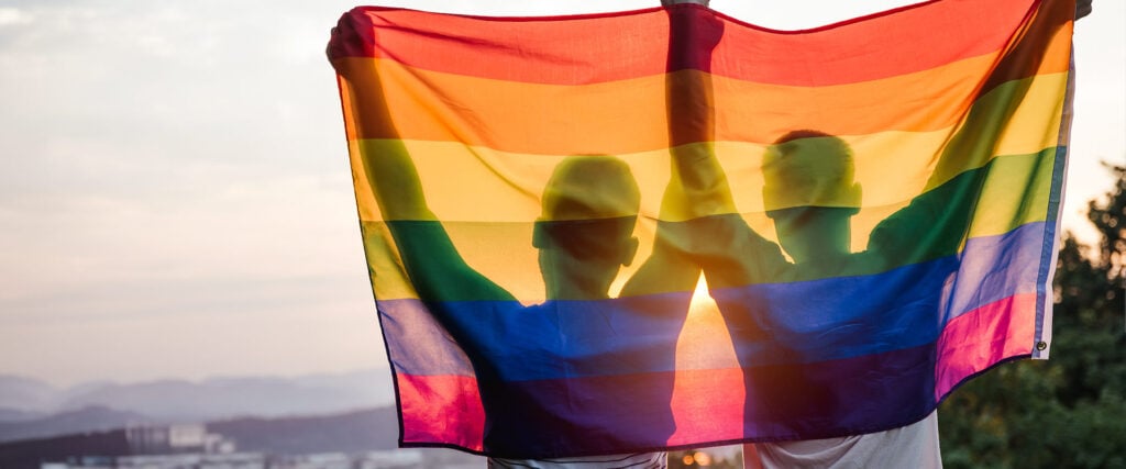 Two people hold up the lgbtq flag