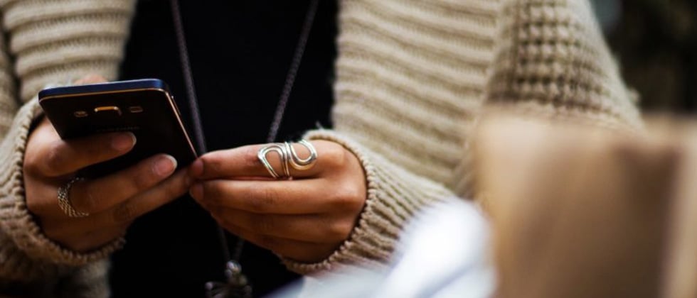 Man and woman both sitting on cell phone as symbol for dating red flags