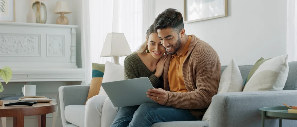 A couple looking at a laptop on their couch.