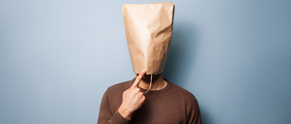 A man standing with a brown paper bag over his head