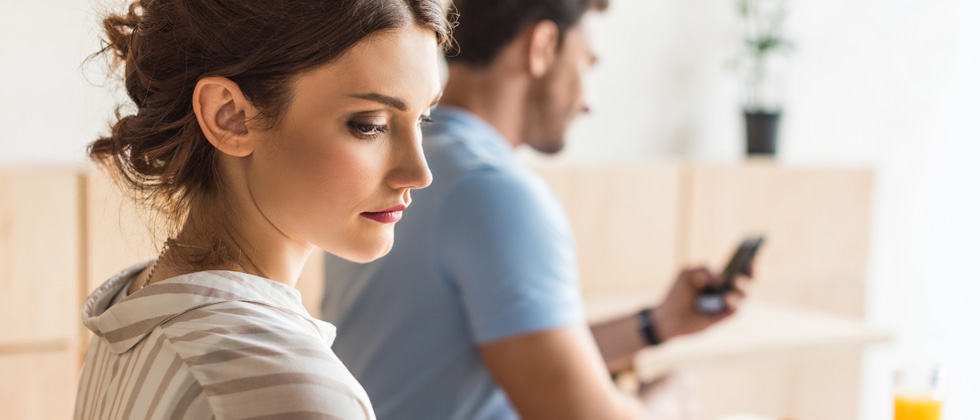 Woman sitting behind her boyfriend looking like she has a secret