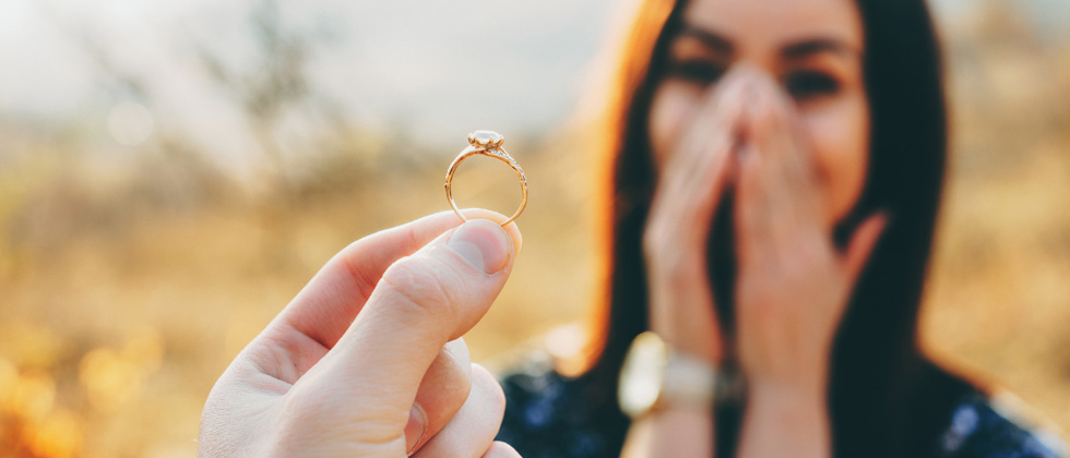 A surprised and delighted woman being proposed and shown the ring