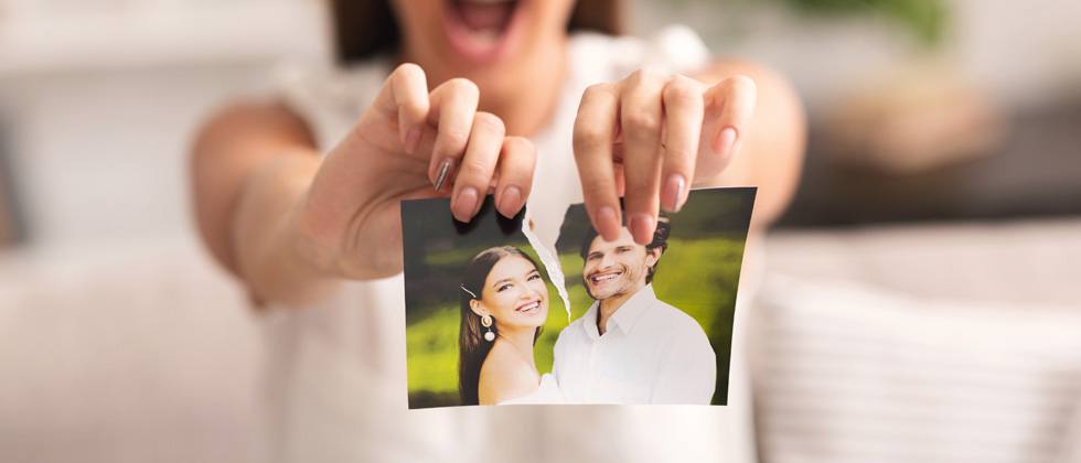 A woman tearing a picture of a couple down the middle