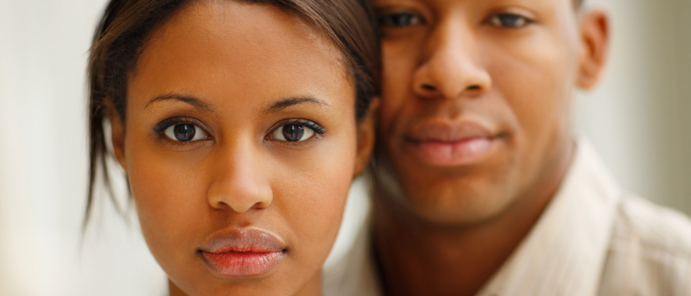 A stoic couple standing together and staring into the camera