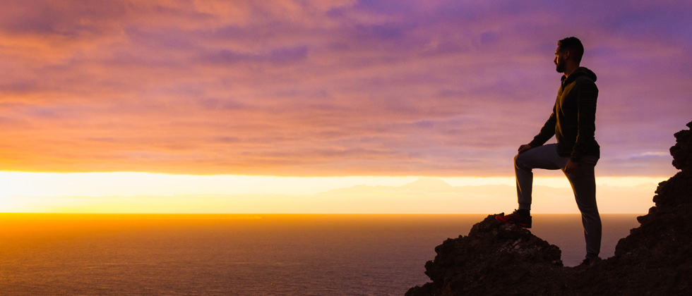 Man standing on top of a mountain at sunrise after a hike