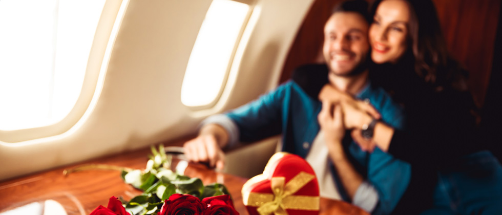 Couple sitting on a private airplane with chocolates and flowers