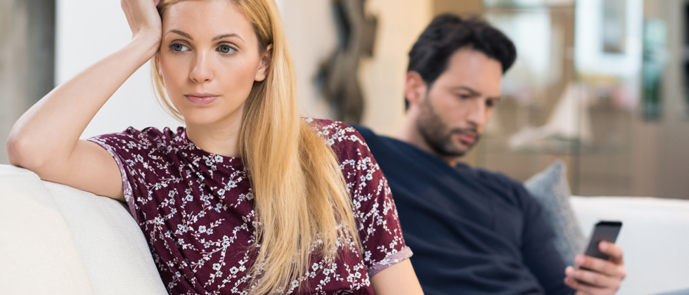 Man texting in the background while sitting next to an upset woman