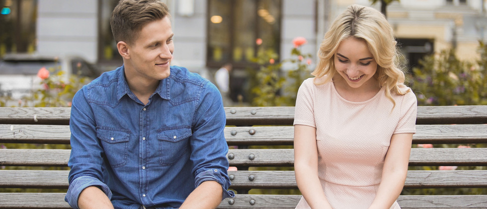 A young couple flirting on a park bench together