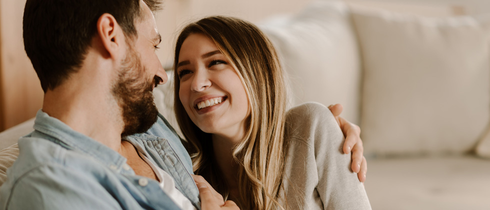 Couple sitting on the couch looking longingly into each other's eyes