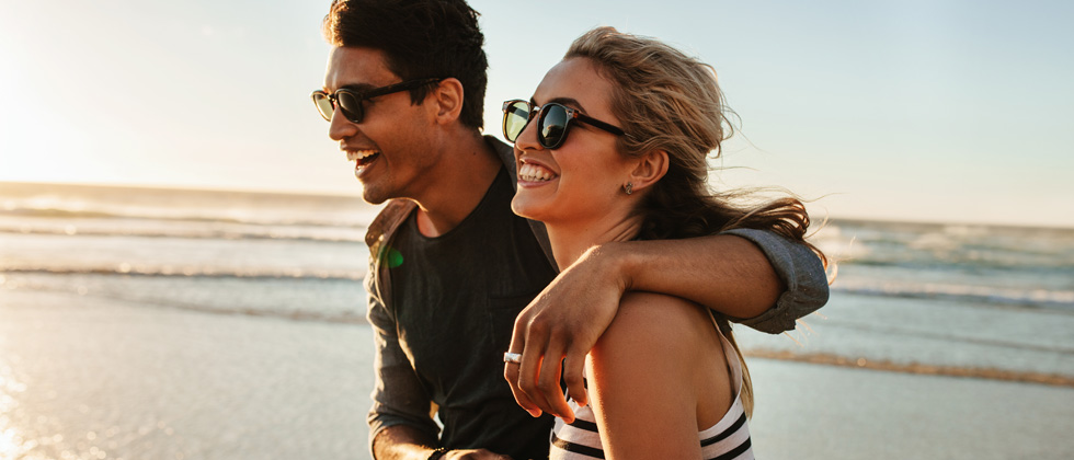 A couple walking with their arms around each other down the beach