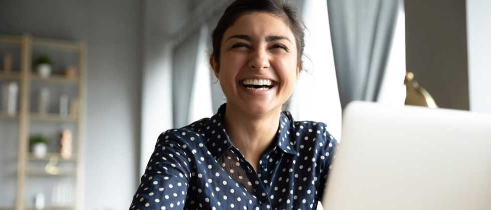 A woman working on her laptop and laughing