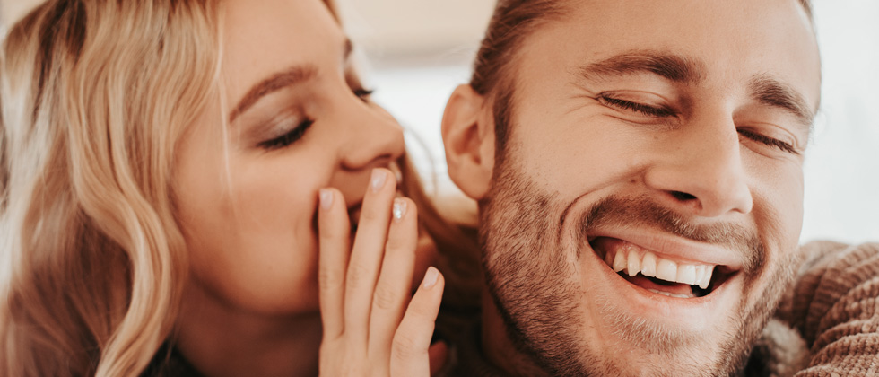 Woman whispering something flirty into her boyfriend's ear