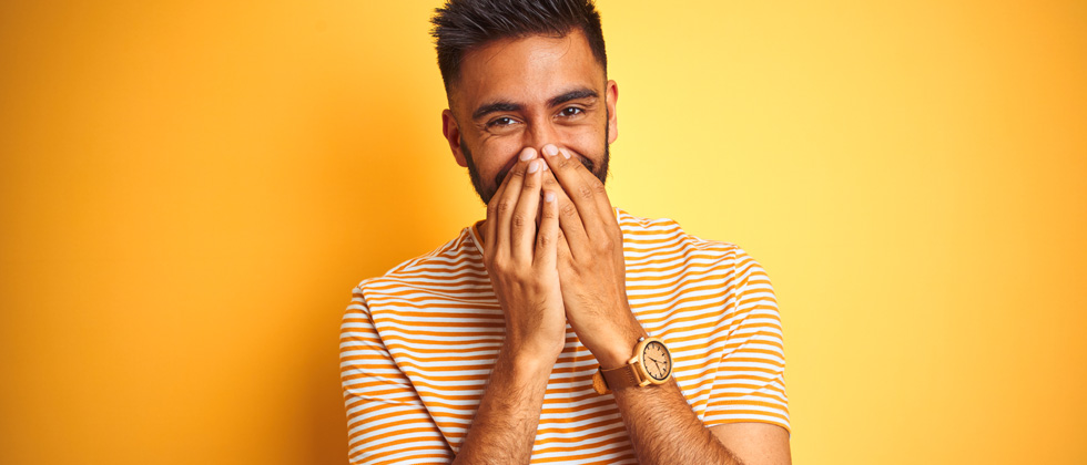 A man holding his hands over his mouth giggling