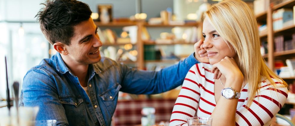 A guy flirting with a woman and brushing her hair behind her ear