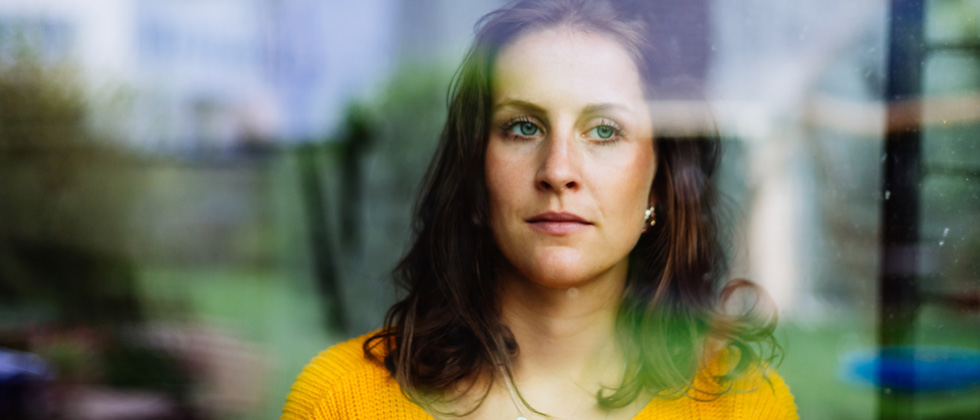 A solemn woman gazing out a window looking into the distance