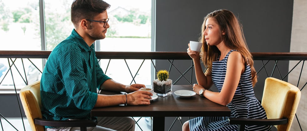 A young couple sitting at a restaurant drinking coffee