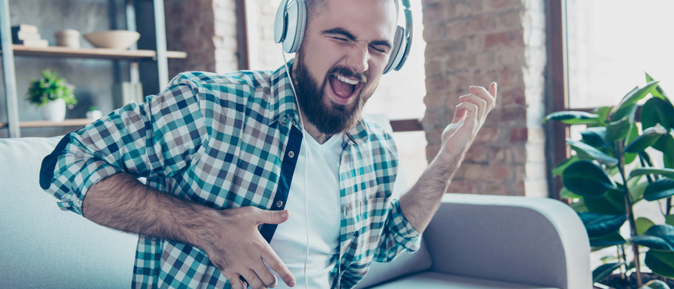A guy with handphones on rocking out with his invisible guitar