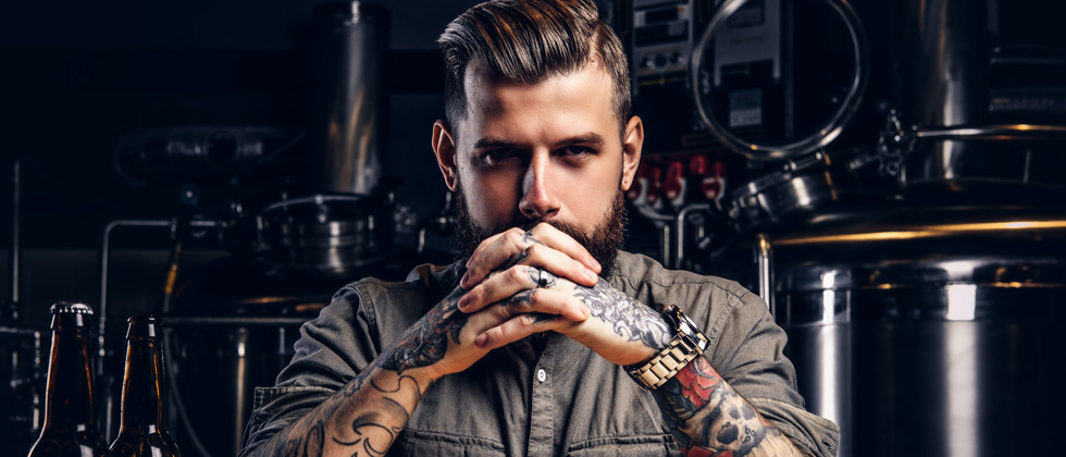 A young man with lots of tattoos staring aggressively into the camera