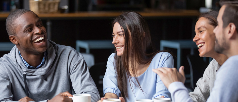 Two couples on a date laughing together & one woman gazes at her man