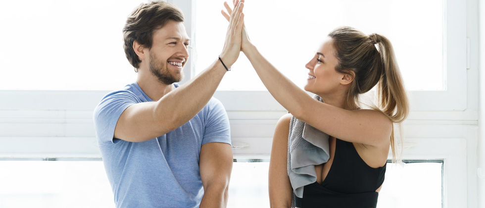 A young couple giving each other a high-five after a workout