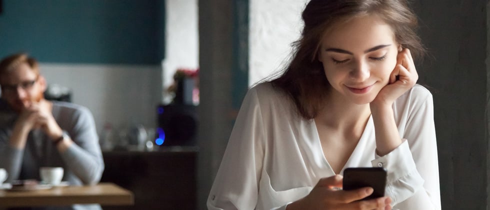 A woman gently smiling while looking down at her phone