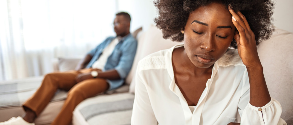 A couple sitting on the couch looking distant from each other
