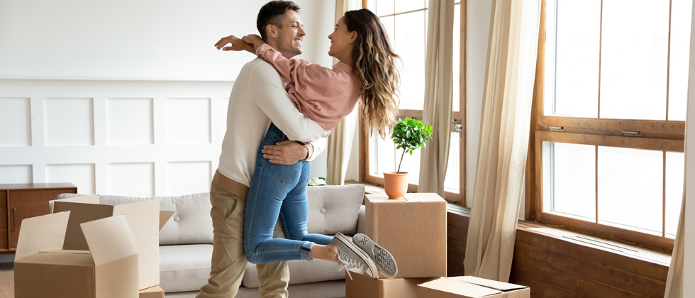 A couple hugging in their living room while unloading boxes
