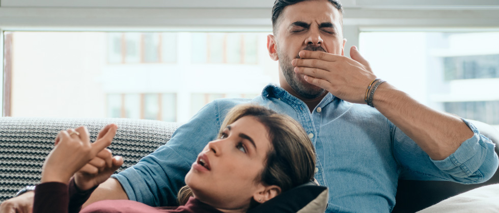 Woman laying on her man's lap while he's yawning as she talks