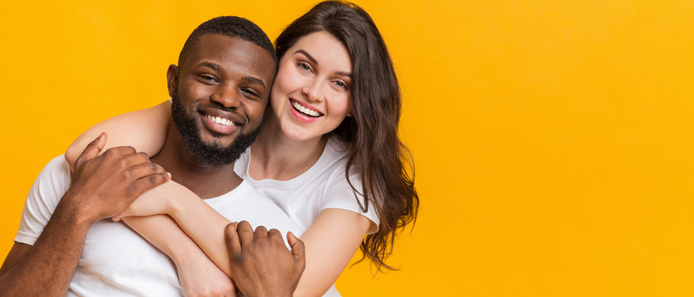 An interracial couple holding each other and smiling