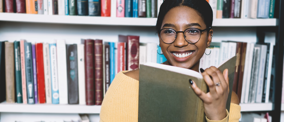 A woman sitting in front of a bookcase reading a book