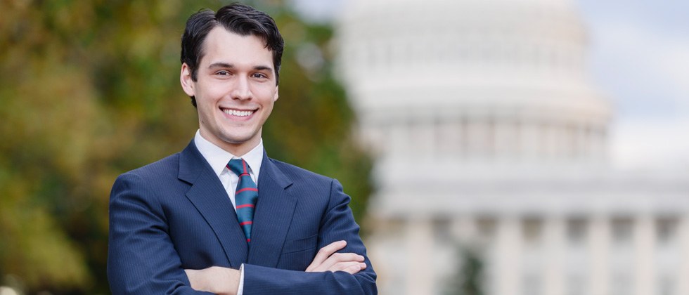 A man dressed in a suit & tie in front of a capital building