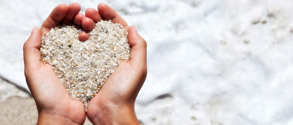 Someone holding sand in their hands making it form a heart