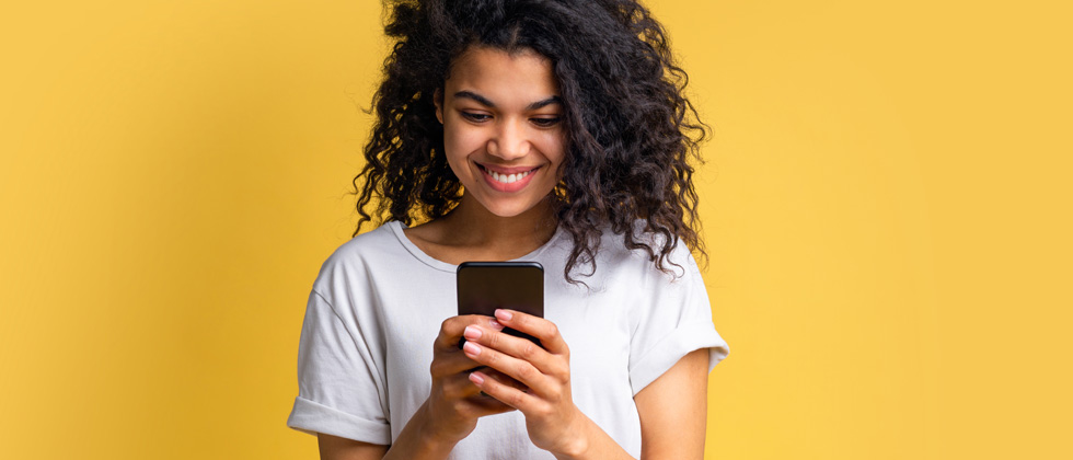A woman standing looking into her phone intensely