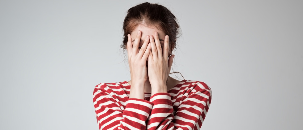 A woman covering her face with her hands