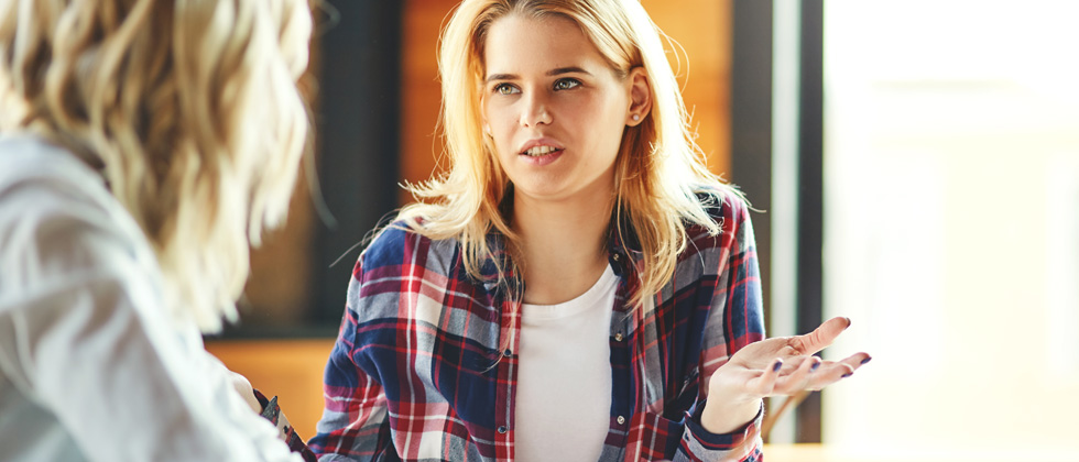 A woman looking annoyed trying to have a conversation with someone