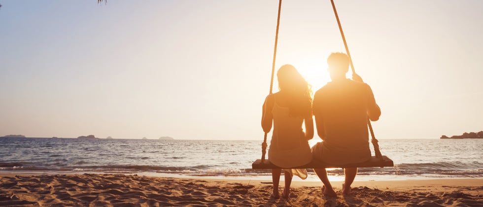 Couple sitting on a swing together on the beach