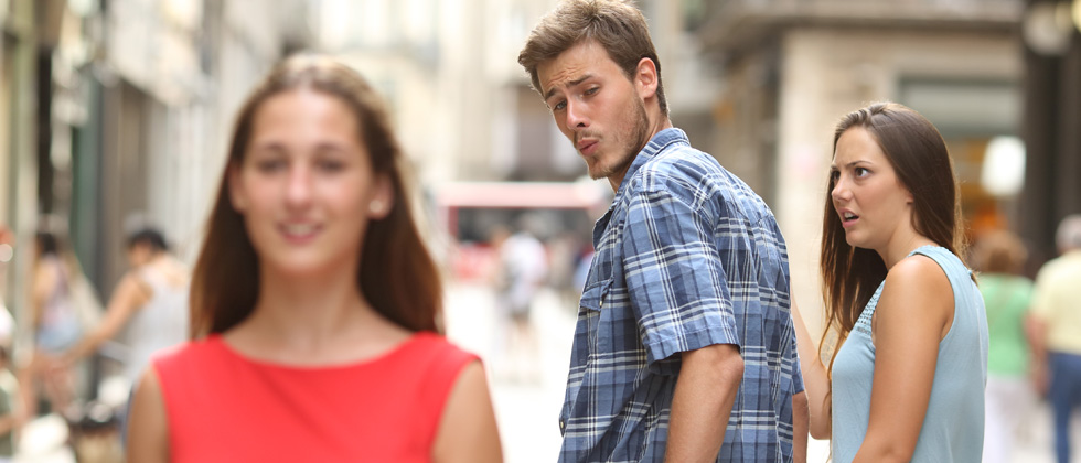 A guy checking out another woman while walking with his girlfriend