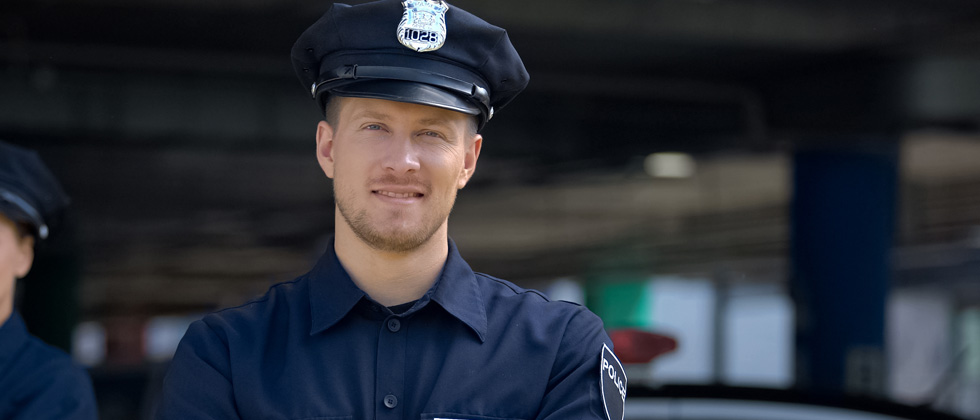 A male police officer standing in uniform smiling for the camera