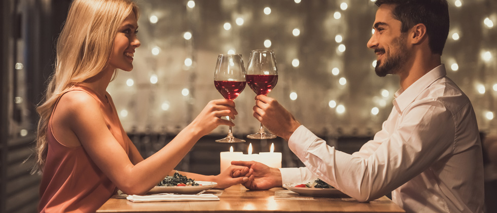 A couple on a date drinking wine and holding hands