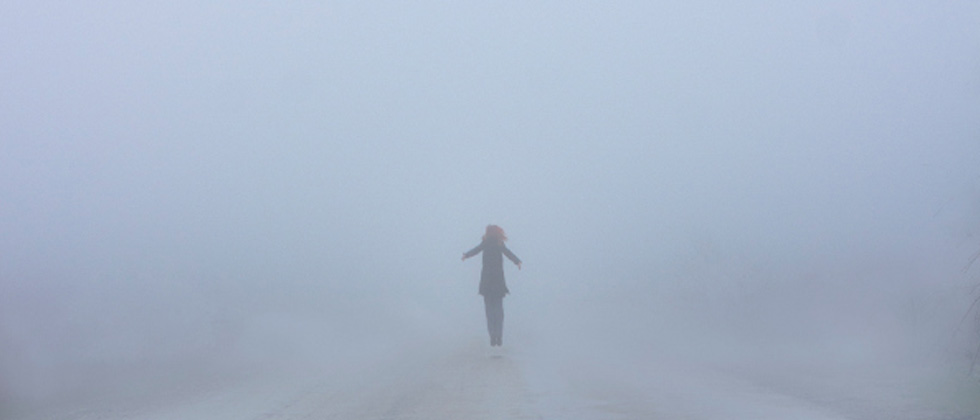 Someone standing at a distance in the middle of a foggy street