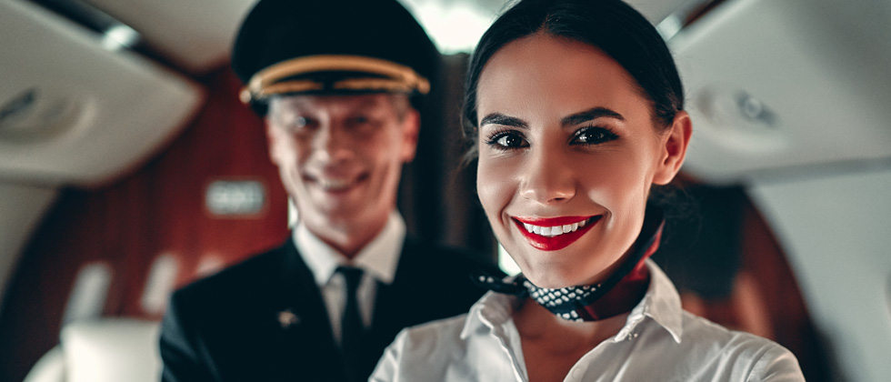 A woman flight attendant standing in a plane cabin with the pilot